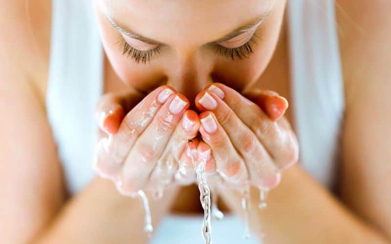 Femme entrain de nettoyer son visage à l'eau claire